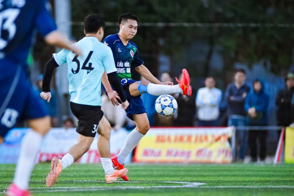Blue team player controls a bouncing ball during midfield play.