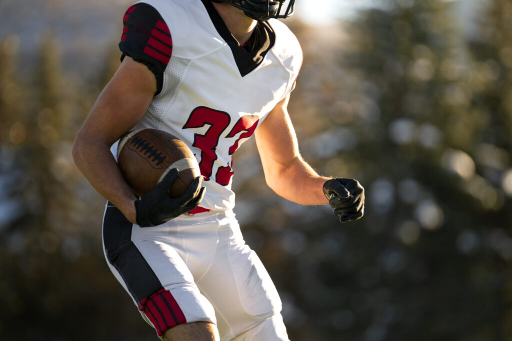 American football player running with ball in white and red uniform.